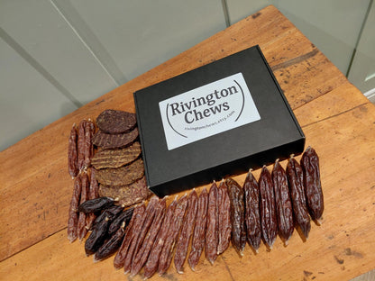 Rivington Chews dog treats on a wooden surface with a branded box.